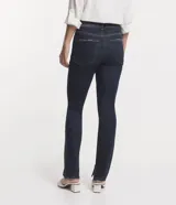 Pantalón de jean corte slim, color azul oscuro, con cierre de botón y cremallera, trabillas en la cintura y aberturas laterales en los bajos.