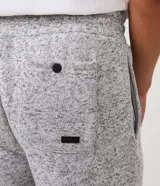 Pantalón de jogging gris jaspeado, con cintura elástica ajustable con cordón, bolsillos laterales y traseros, y puños ajustados.