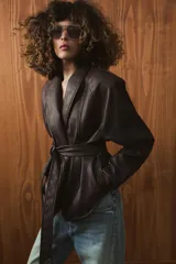 Chaqueta de Zara Woman Collection confeccionada en tejido efecto piel con textura granulada. Presenta cuello solapa, manga larga y cierre frontal con cinturón ajustable mediante lazada. Incluye forro interior.