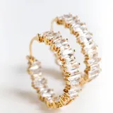 Aros tipo argolla dorados con incrustaciones de cristales blancos.
