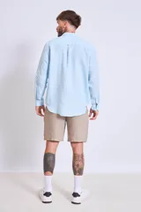 Camisa de corte regular con diseño de rayas verticales finas en tonos claros, cuello clásico y mangas largas con puños abotonados.