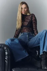 Jean de corte oxford confeccionado en denim azul con lavado desgastado y bigotes. Presenta tiro alto, pierna ancha que se ensancha desde la cadera hacia el ruedo, cierre frontal con botón y pequeñas roturas decorativas.