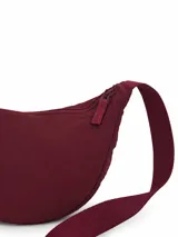 Riñonera de diseño curvo y compacto, con cierre superior y correa regulable que permite llevarla cruzada o al hombro.