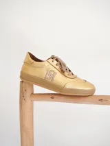 Championes de cuero color dorado con cordones marrones y logo bordado en el lateral.
