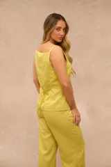 Pantalon de vestir color lima con finas rayas verticales blancas, de corte sastrero y piernas anchas, con bolsillos laterales y trabillas para cinturon.