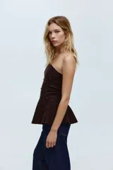 Top strapless de punto color marrón oscuro, con ajuste entallado y peplum acampanado en el ruedo. Presenta cuentas metálicas decorativas distribuidas por toda la prenda y borde interno de silicona en el escote para mayor sujeción.