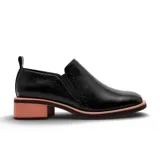 Zapato tipo mocasín de cuero negro con detalles de perforaciones decorativas tipo brogue y taco cuadrado bajo con acabado texturizado en tono rosado.