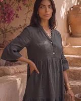 Vestido corto verde militar de lino, con cuello mao, escote en V con botones, mangas tres cuartos acampanadas con volados y falda con volado en el ruedo.