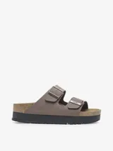 Sandalia tipo slide de dos tiras ajustables, color marrón topo, con hebillas metálicas color oro rosa. Presenta una plataforma gruesa de color negro sobre la clásica suela de corcho anatómica de Birkenstock.