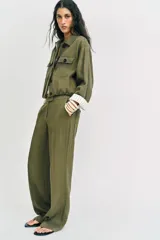 Pantalón recto de tiro bajo en color verde militar, con nervios marcados en la parte delantera, bolsillos frontales y cierre con cremallera, botón interior y ganchos.