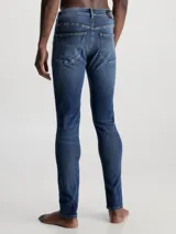 Jeans de hombre con ajuste skinny, talle bajo y pierna estrecha. Denim de algodón elástico con lavado azul oscuro vintage.