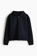 Campera con capucha de tejido efecto neopreno, con cierre frontal completo, hombros caídos y bolsillos delanteros abiertos. Presenta un corte holgado y diseño minimalista.