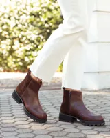 Botinetas de caña baja confeccionadas en cuero vacuno color chocolate, con paneles laterales en gamuza al tono. Presentan suela track de goma negra, cierre lateral interno y puntera redondeada.