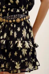 Falda short negra con estampado floral metalizado en tono dorado, de tiro alto y diseño con volados escalonados.