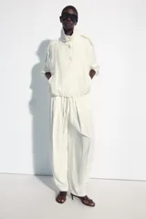 Pantalón fluido de tiro medio, color blanco, con cintura elástica ajustable con cordones, bolsillos laterales y bajo ajustable con trabilla y botón a presión.