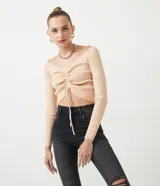 Blusa cropped de punto acanalado color beige, con escote ombro a ombro, manga larga y cordón ajustable con lazo.