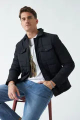 Campera negra de nylon capitoneada, con cuello medio y bolsillos tipo sobre con botón.