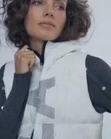 Chaleco largo negro estilo puffer con capucha y cierre frontal.