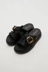 Sandalias planas de eco cuero color bordó, con tiras cruzadas y hebilla metálica dorada.