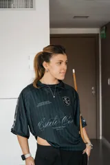 Camiseta de fútbol estilo boxy de manga corta y cuello polo, en color negro con sutiles rayas verticales. Presenta inscripciones estampadas y escudo bordado en el pecho.