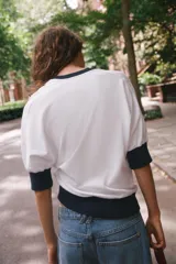 Camiseta de algodón color blanco con cuello redondo, mangas cortas y bajo abullonado, con detalles en color azul marino en el cuello, los puños y el ruedo.