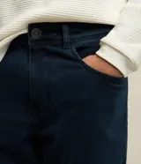 Pantalón de jean corte slim, color azul oscuro, con trabillas en la cintura, cierre frontal y bolsillos laterales y traseros.