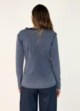 Remera de manga larga color azul, con cuello redondo adornado con un detalle de textura desflecada o peluda en el borde.