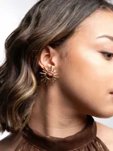 Aros dorados con diseño en forma de sol, de estilo llamativo y elegante.