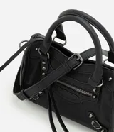 Cartera satchel Satinato de color negro, confeccionada en poliuretano. Cuenta con asas de mano fijas, correa larga removible, bolsillos frontales con cierre, tachas metálicas decorativas y tiras colgantes.