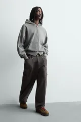Pantalón de corte relaxed fit confeccionado en algodón, color gris oscuro. Presenta bolsillos delanteros, bolsillos laterales tipo cargo en las perneras y cierre frontal con cremallera y botón.