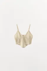 Top crop de punto color beige con escote en pico y tirantes finos ajustables. Presenta diseño con tejido calado y bajo de acabado asimétrico.