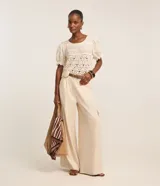 Pantalón pantalona de corte amplio, color beige, con trabillas en la cintura, pliegues delanteros y bolsillos cargo en los laterales.