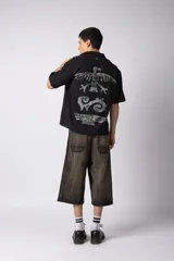 Camisa de manga corta confeccionada en lino, con cuello clásico y cierre frontal de botones. Presenta un diseño de corte relajado y textura aireada, con una estampa trasera que reinterpreta símbolos andinos en clave urbana.