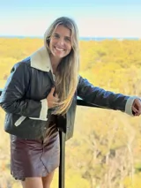 Campera de cuero de oveja italiano con diseño slouchy, cuello de piel sintética desmontable y detalles de piel en puños y bolsillos. Presenta cierre frontal con botones a presión.