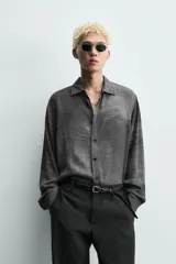 Camisa de corte relajado confeccionada en tejido fluido de viscosa, con cuello solapa, manga larga con puños abotonados y cierre frontal de botones. Presenta un estampado con efecto lavado.