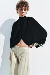 Top corto negro de punto fino, con cuello redondo y mangas largas abullonadas con pliegues.