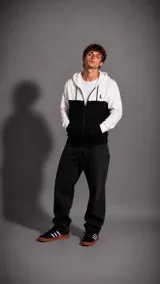 Campera con capucha y cierre frontal, de diseño bicolor con bloques en blanco y negro. Presenta un pequeño logo bordado en el pecho y bolsillos frontales.