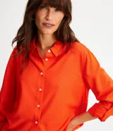 Camisa de manga larga color verde lima, con cuello camisero y botonadura frontal. Presenta un dobladillo trasero más largo que el delantero.