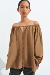 Blusa de lino color blanco, con escote recto ajustable mediante cordón y hombros descubiertos. Cuenta con manga larga abullonada terminada en elástico.