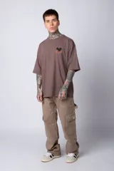 Remera negra de algodón de corte oversize, con mangas cortas y cuello redondo. Estampado pequeño en el frente y diseño grande en la espalda con Mickey Mouse y caracteres orientales en tonos rojizos.