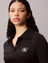 Chomba de Calvin Klein confeccionada en tejido canalé de algodón con elastano. Presenta cuello tipo polo con cartera de dos botones, mangas cortas y un ajuste estructurado. Incluye una pequeña insignia de la marca en el dobladillo inferior.