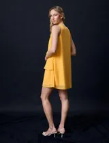 Vestido corto de gasa color amarillo, con escote en V, sin mangas y forro interno a tono.