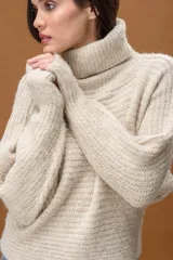 Sweater de punto con cuello alto, manga larga y diseño holgado. Presenta una textura suave con un sutil acabado brillante.