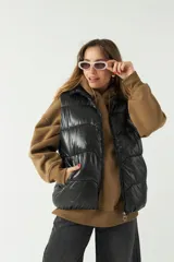 Chaleco puffer negro con cuello alto y cierre frontal. Tiene bolsillos laterales con cierre y diseño acolchado con pespuntes en pico.
