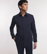 Camisa de vestir blanca de algodón con textura maquinetada, cuello camisero y mangas largas.