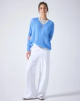 Sweater de punto fino color gris claro, con cuello en V y mangas largas. El tejido parece ser ligeramente transparente o muy liviano.