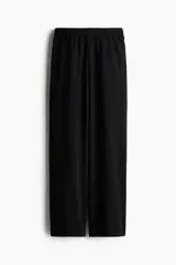Pantalón negro de corte ancho, con cintura elástica y bolsillos laterales.
