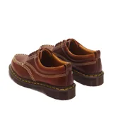 Zapatos Dr. Martens modelo Lowell de cuero marrón, con cordones, pespuntes amarillos en la suela y costuras destacadas en la puntera.