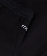 Pantalón ancho negro de corte relajado, confeccionado en mezcla de algodón y lino. Presenta cinturilla elástica de punto con cordón y trabillas, bolsillos laterales inclinados, etiqueta sobre el bolsillo izquierdo, minirayas bordadas bajo el bolsillo izquierdo y un bolsillo de ribete doble en la espalda.