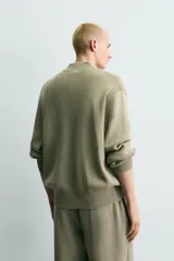 Chaqueta relaxed fit de tejido de punto de algodón, color verde militar, con cuello subido, manga larga, acabados en rib y cierre frontal con cremallera. Presenta efecto lavado.